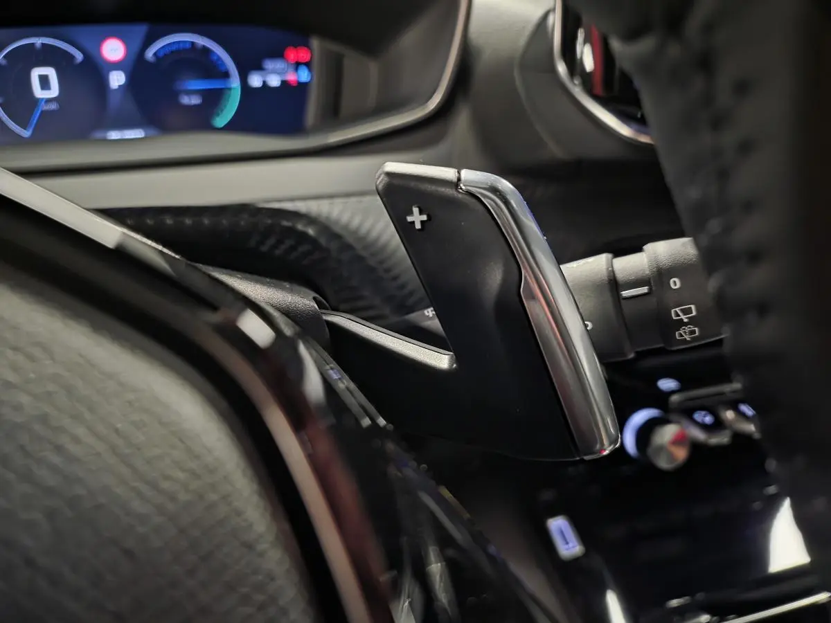 Gros plan sur la palette de changement de vitesse droite en chrome et noir dans l'habitacle du Peugeot 2008 gris hybride 2025.