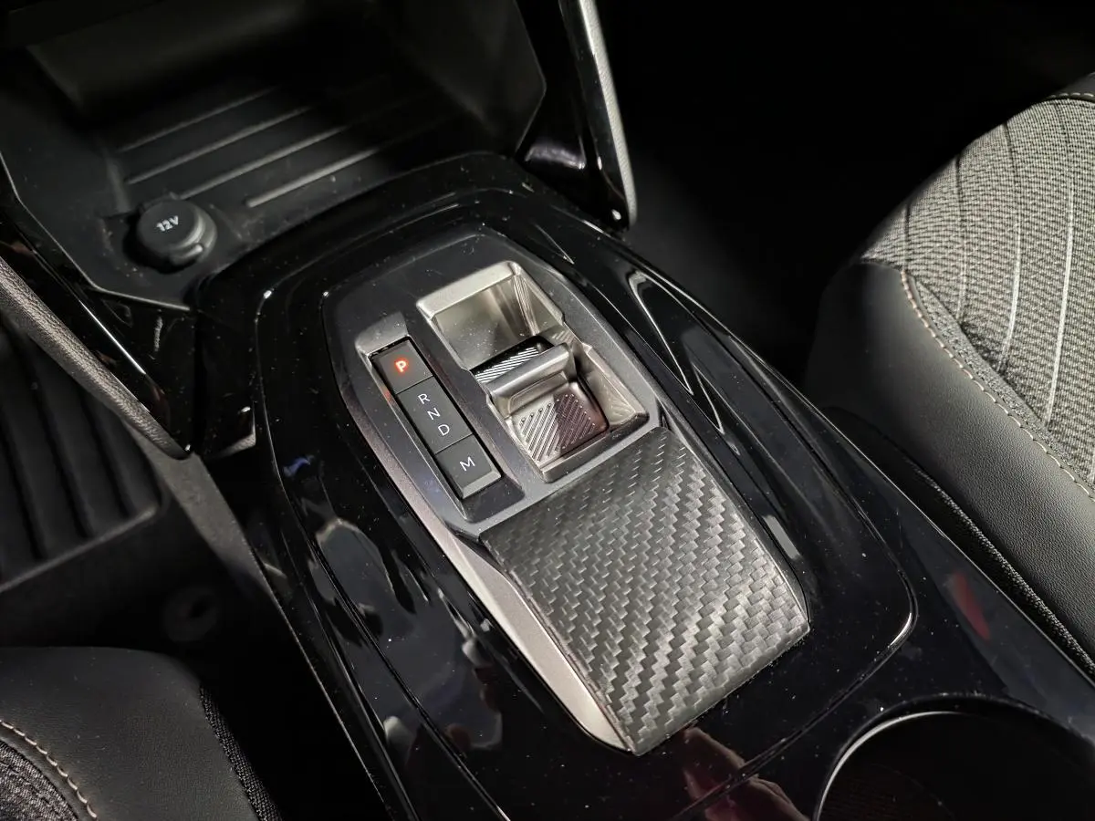 Vue rapprochée de la console centrale noire brillante avec sélecteur de boîte auto et tissu gris sur siège PEUGEOT 2008 2025.