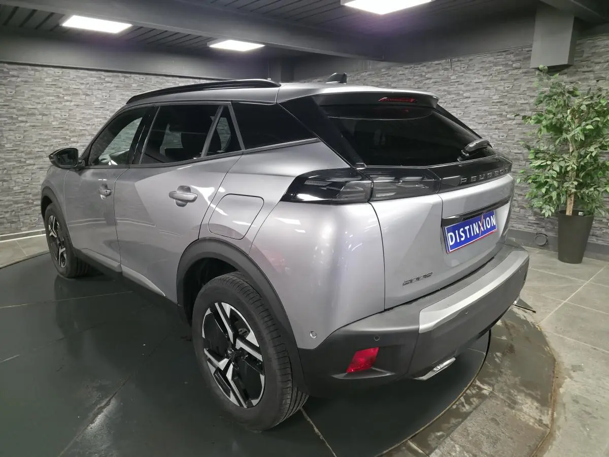 Vue 3/4 arrière droite d'un Peugeot 2008 gris métallisé avec toit noir et feux arrière LED distinctifs.