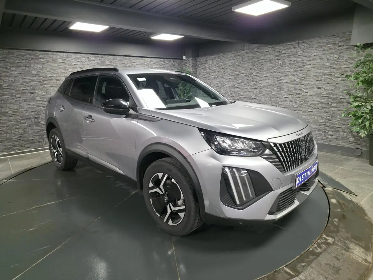 Peugeot 2008 gris en 3/4 avant droit, avec calandre noire à marquage vertical et jantes alliage bi-ton.