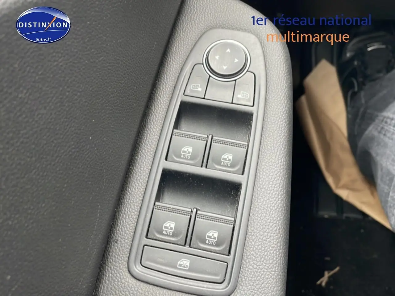 Gros plan sur les commandes de lève-vitres et rétroviseurs côté conducteur d'une Renault Clio V blanche, intérieur noir.