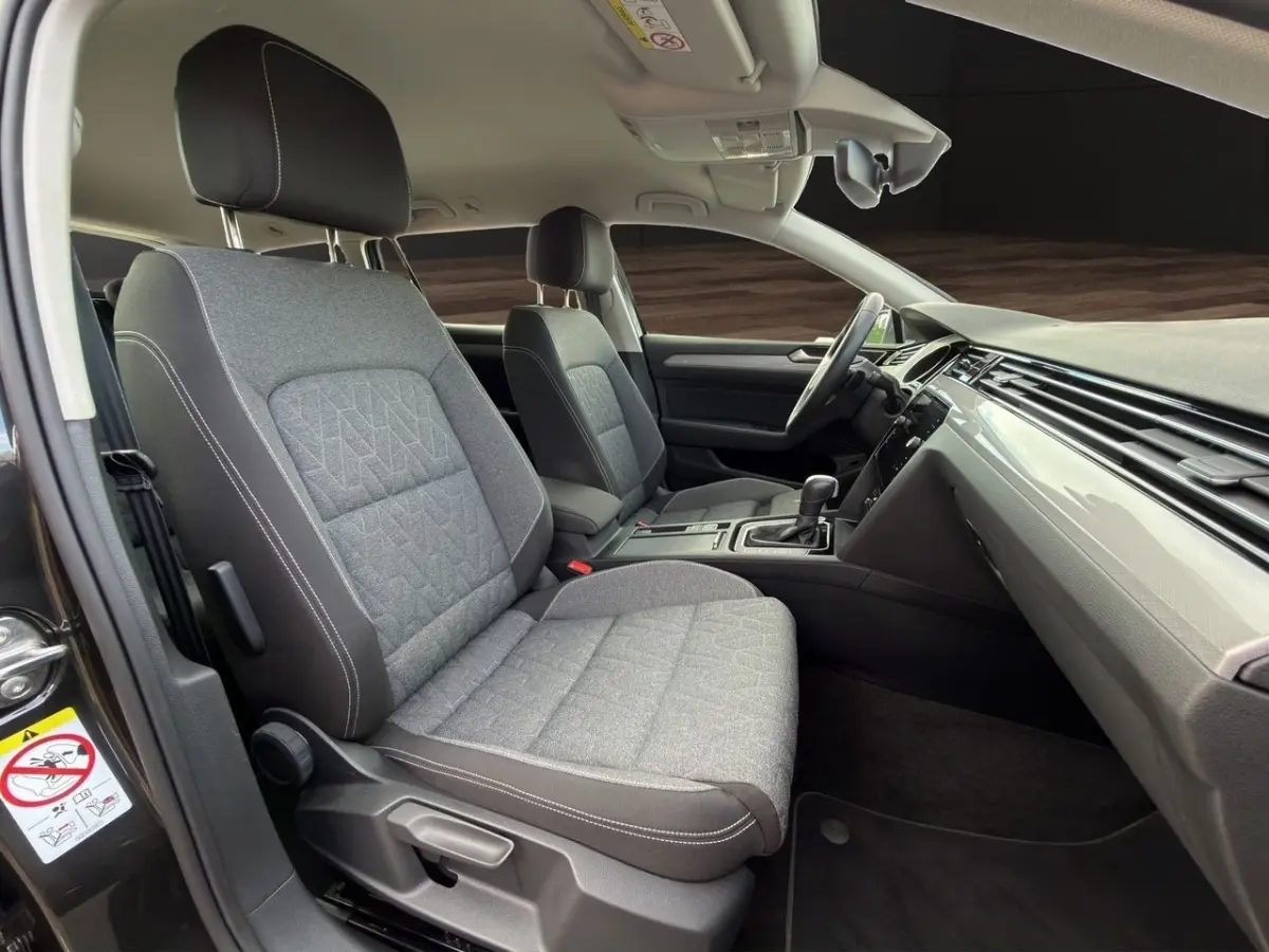 Intérieur avant de la Volkswagen Passat 2.0 TDI 2022, vue côté conducteur avec sièges gris et tableau de bord noir.