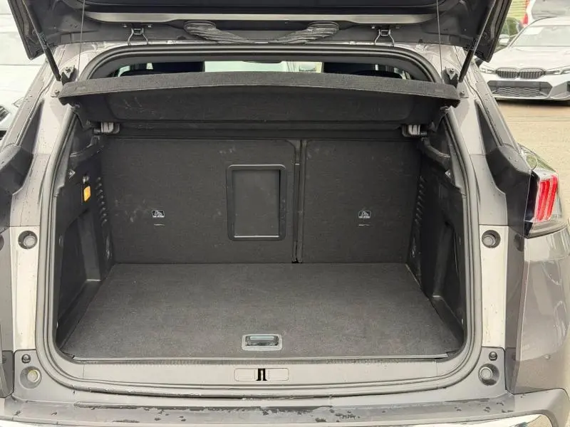 Coffre ouvert vu de l'arrière du Peugeot 3008 Hybride Rechargeable gris titane, montrant un espace de chargement propre et spacieux.