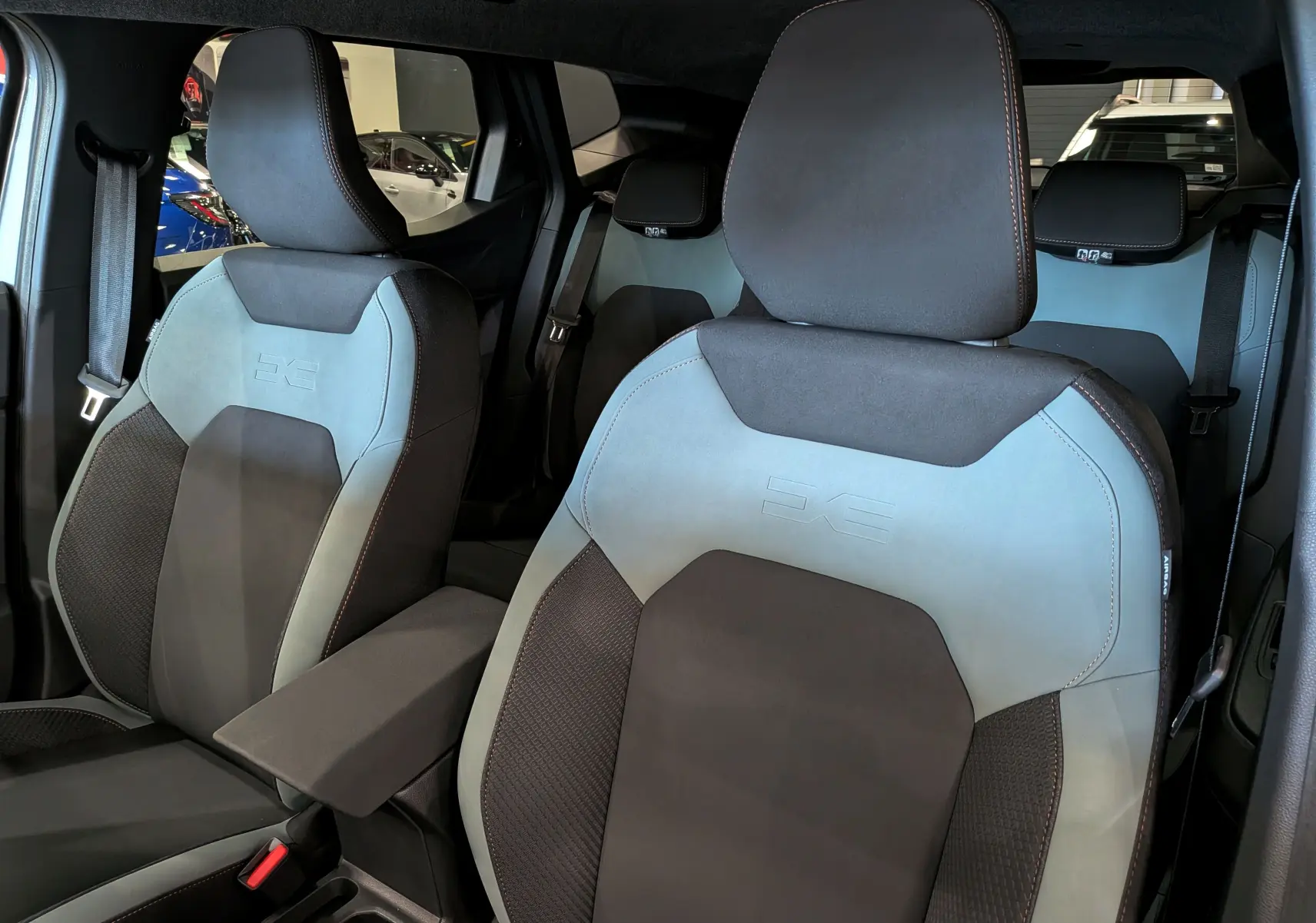 Vue intérieure des sièges avant gris clair et noir du Dacia Duster ECO-G 120 CH AUTO EXTREME 2026 avec logo brodé sur les appuie-têtes.
