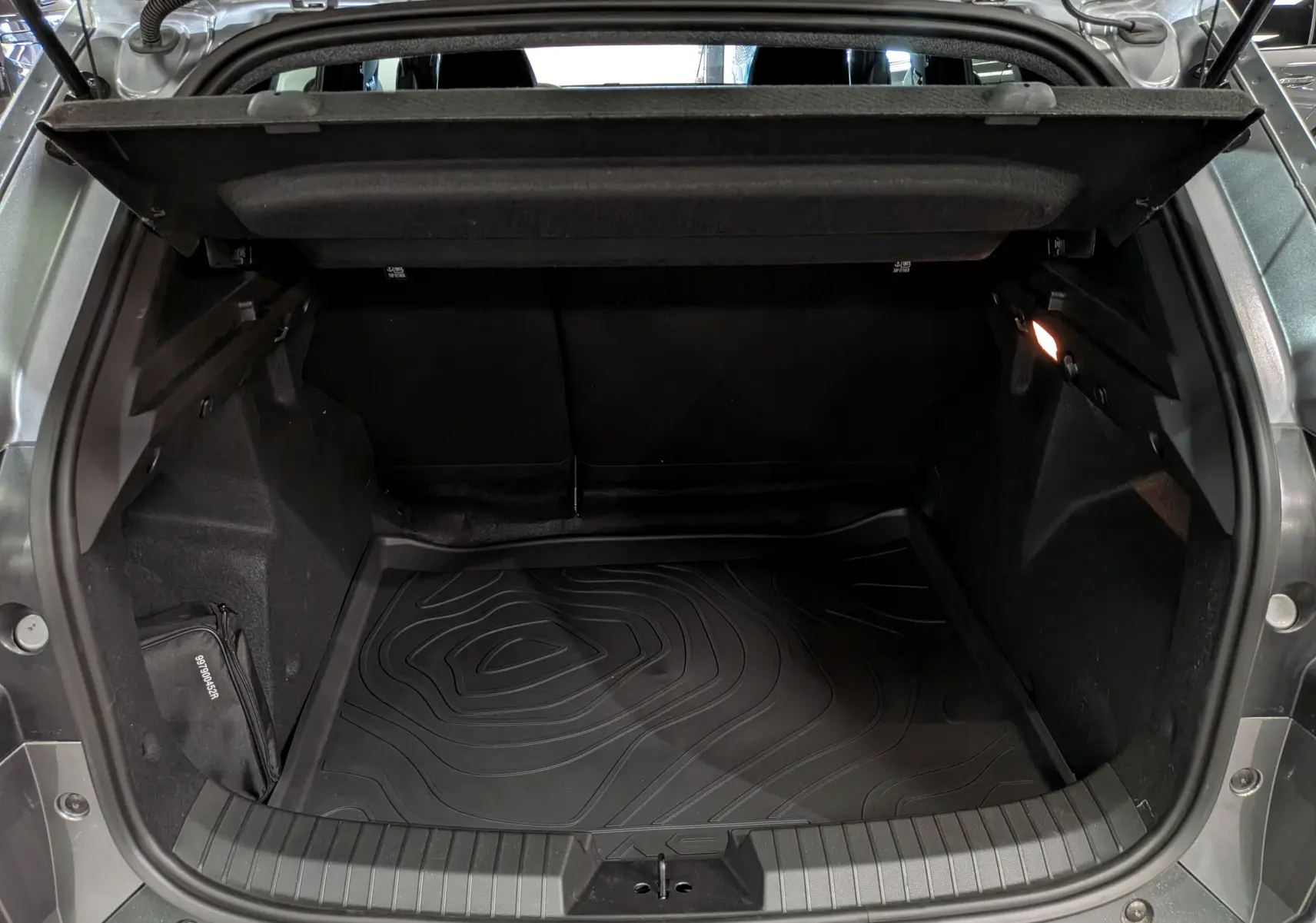 Coffre ouvert du Dacia Duster gris schiste 2026, vue arrière montrant l’espace de chargement avec tapis de protection noir.