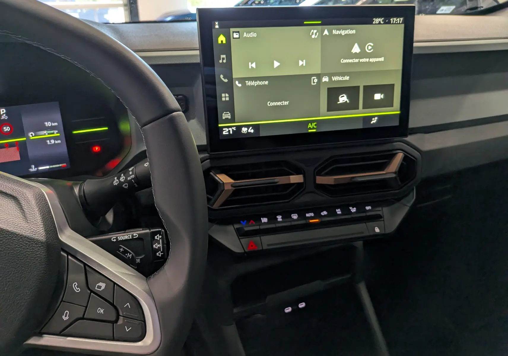 Vue intérieure du tableau de bord du Dacia Duster 2026 gris schiste, avec écran tactile central et commandes au volant visibles.