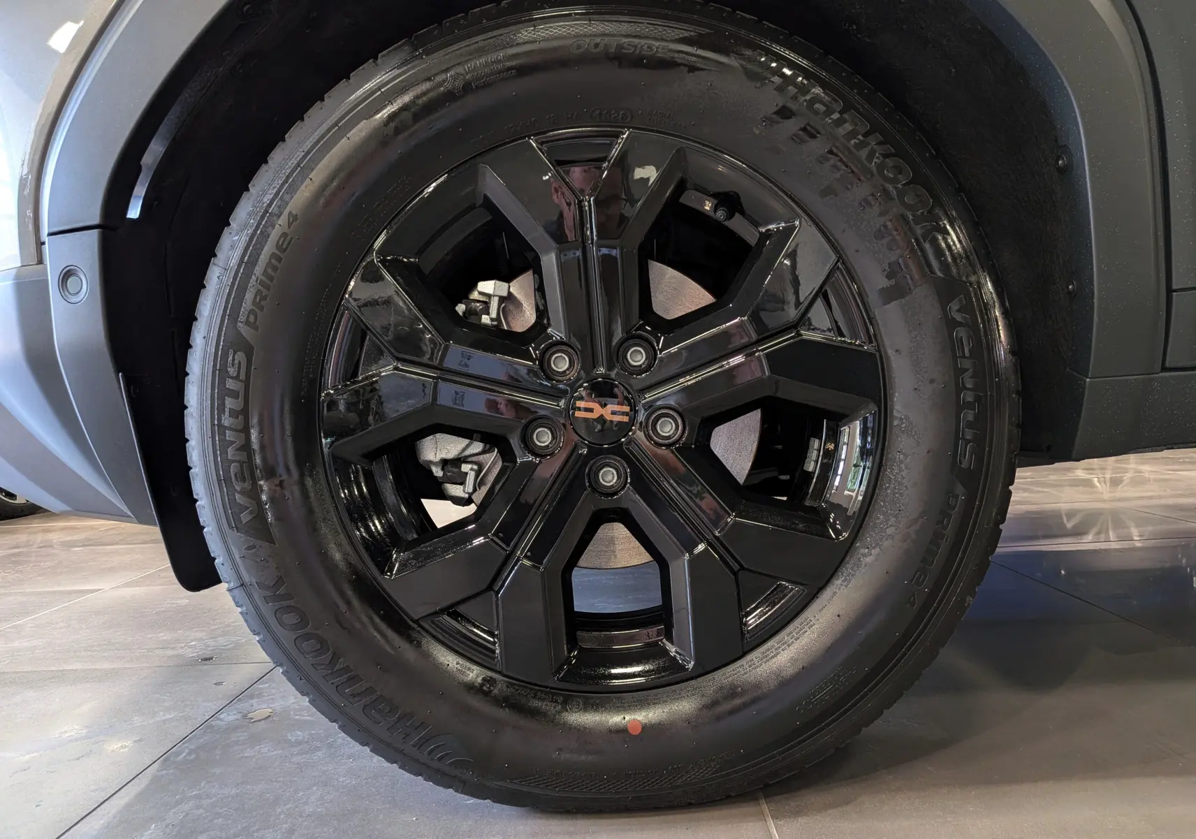 Gros plan sur la roue avant gauche du Dacia Duster 2026 gris schiste avec jante noire brillante et pneu Hankook.