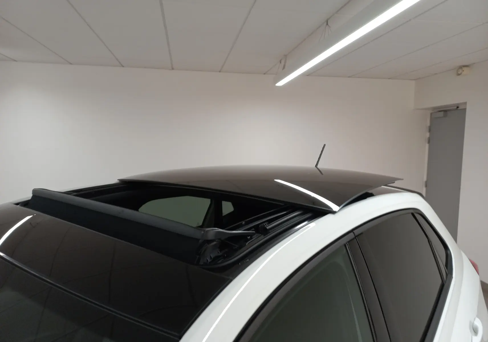 Vue rapprochée du toit ouvrant électrique noir ouvert sur une Volkswagen Polo GTI blanc pur, angle arrière droit.