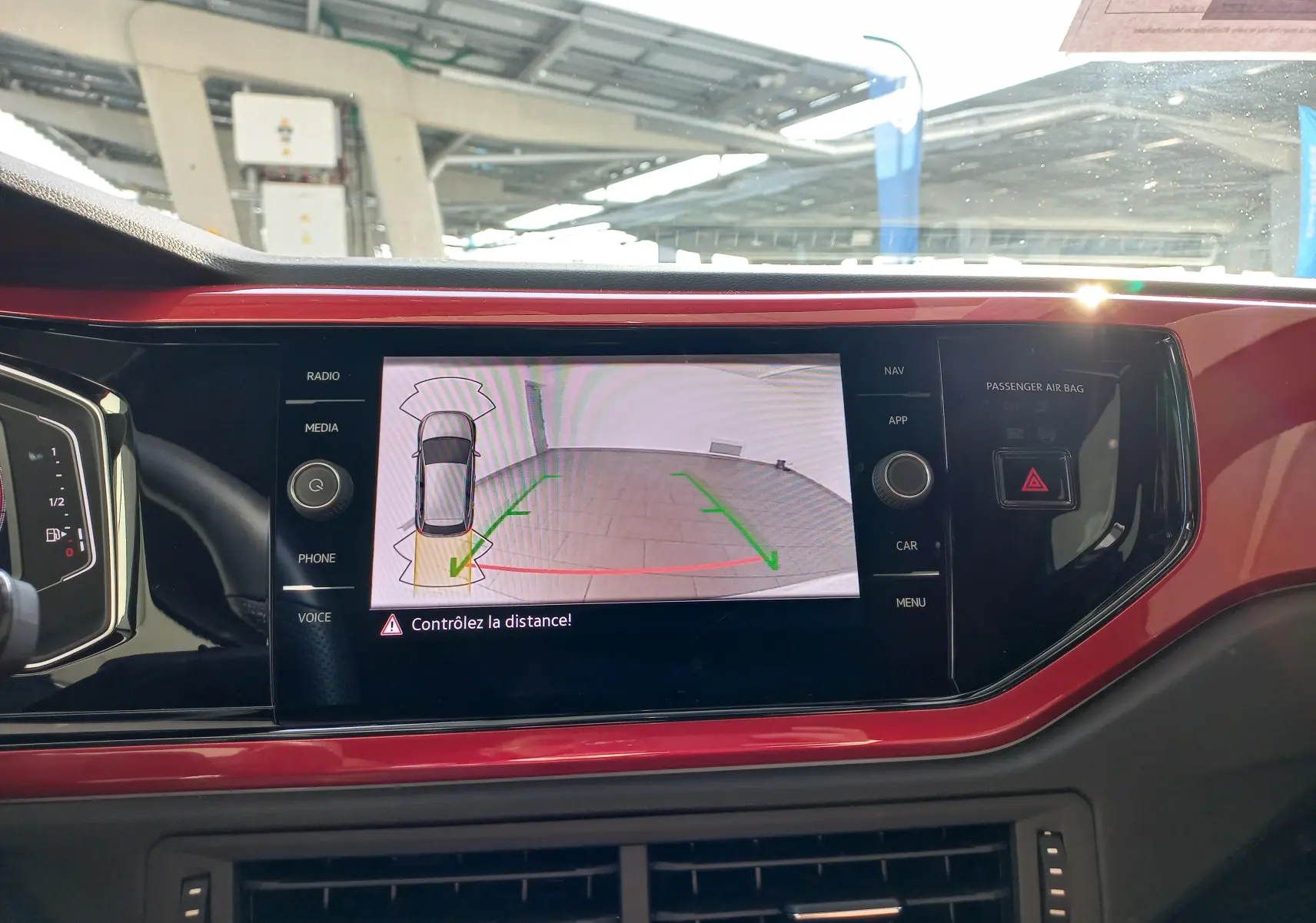 Vue rapprochée de l'écran central rouge de la Volkswagen Polo 2024 affichant la caméra de recul avec guidage vert et rouge.