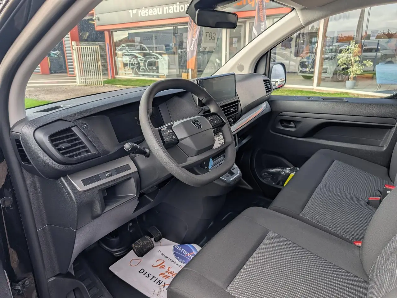 Intérieur avant du Peugeot Expert Fourgon noir 2025, vue côté conducteur avec tableau de bord et banquette passager grise.