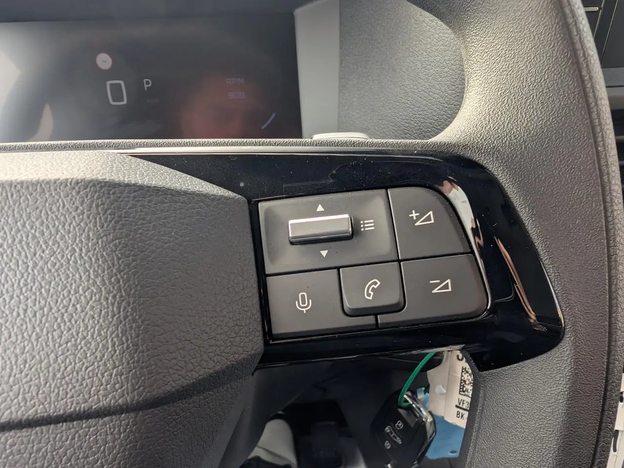 Gros plan sur les commandes au volant à droite du Peugeot Expert Fourgon noir, avec combiné numérique en arrière-plan.