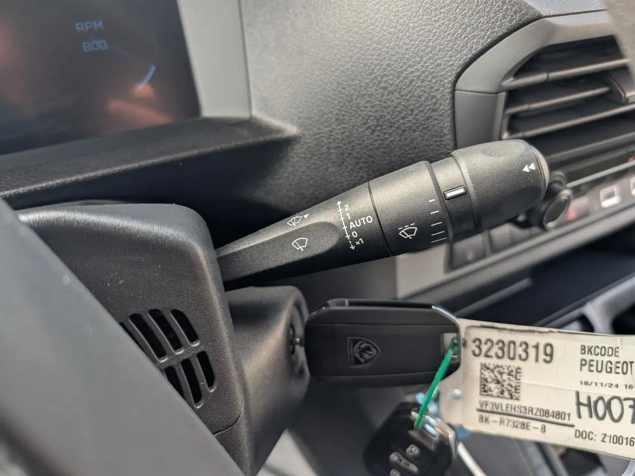 Gros plan sur la manette d’essuie-glace noire et la clé insérée dans le contacteur du Peugeot Expert Fourgon noir.