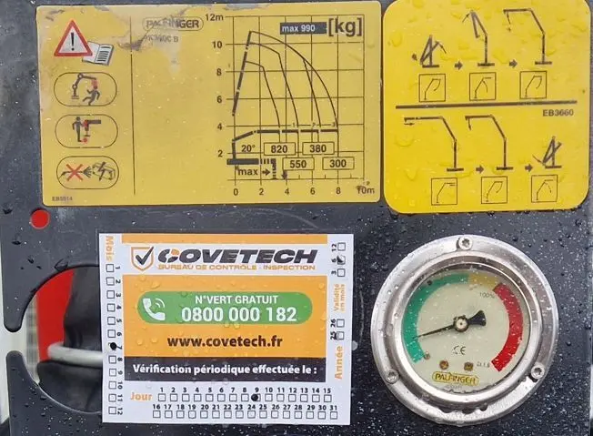 Vue rapprochée du tableau de contrôle de la grue Palfinger sur un Iveco Daily Chassis Cabine blanc, avec étiquettes et manomètre.