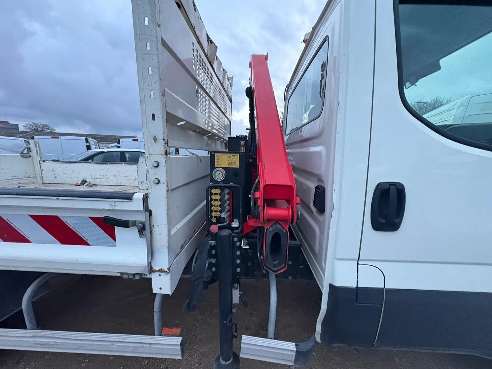 Vue rapprochée de profil droit montrant la cabine blanche et la grue rouge Palfinger entre cabine et benne blanche.