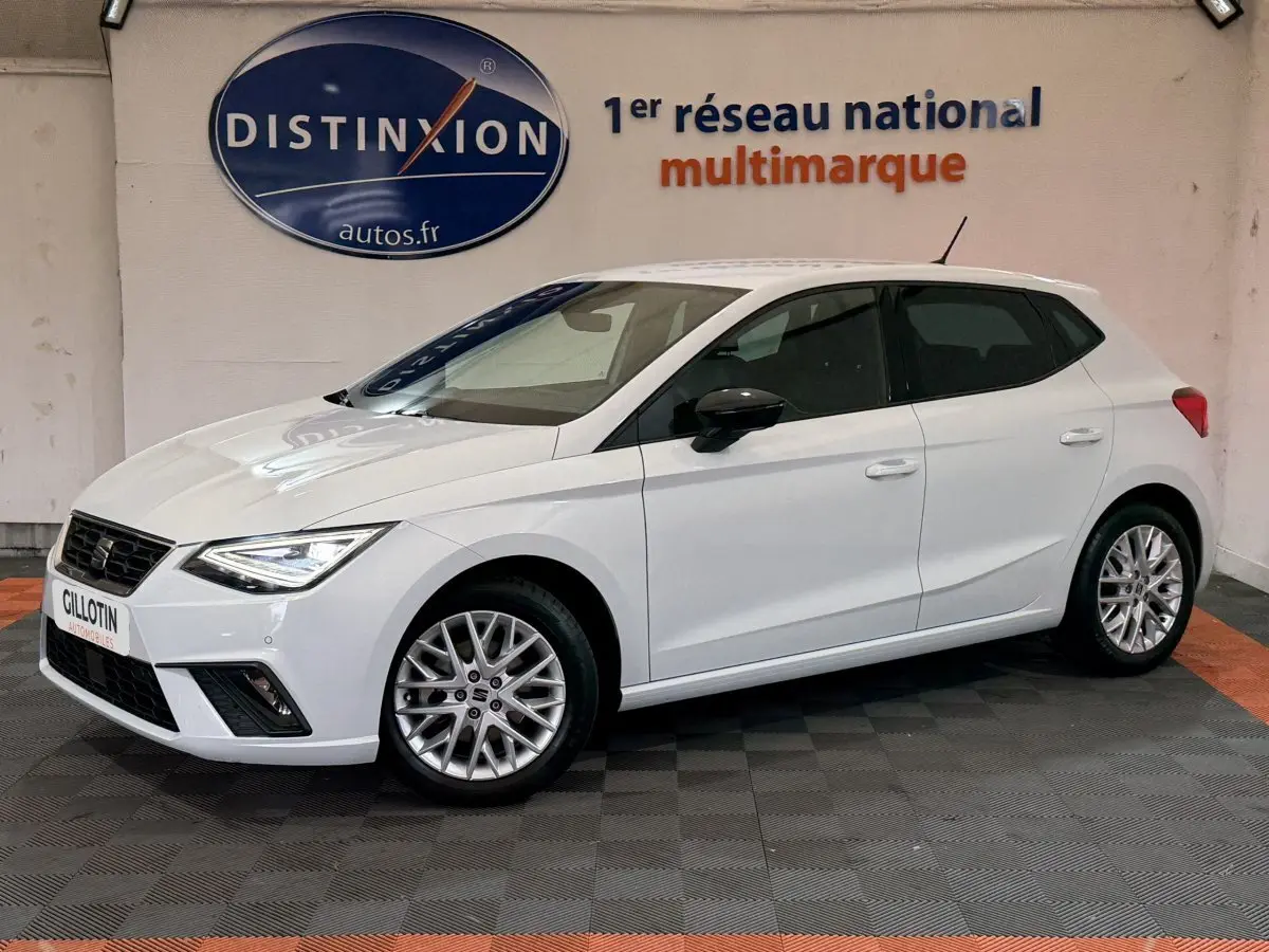 SEAT Ibiza 1.0 TSI 110 FR blanc vue 3/4 avant droit, jantes alliage et phares LED allumés.
