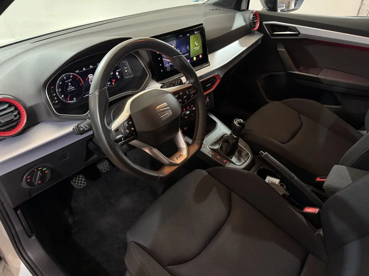 Vue intérieure côté conducteur de la SEAT Ibiza 1.0 TSI 110 FR 2024 avec volant cuir alu et écran tactile central.