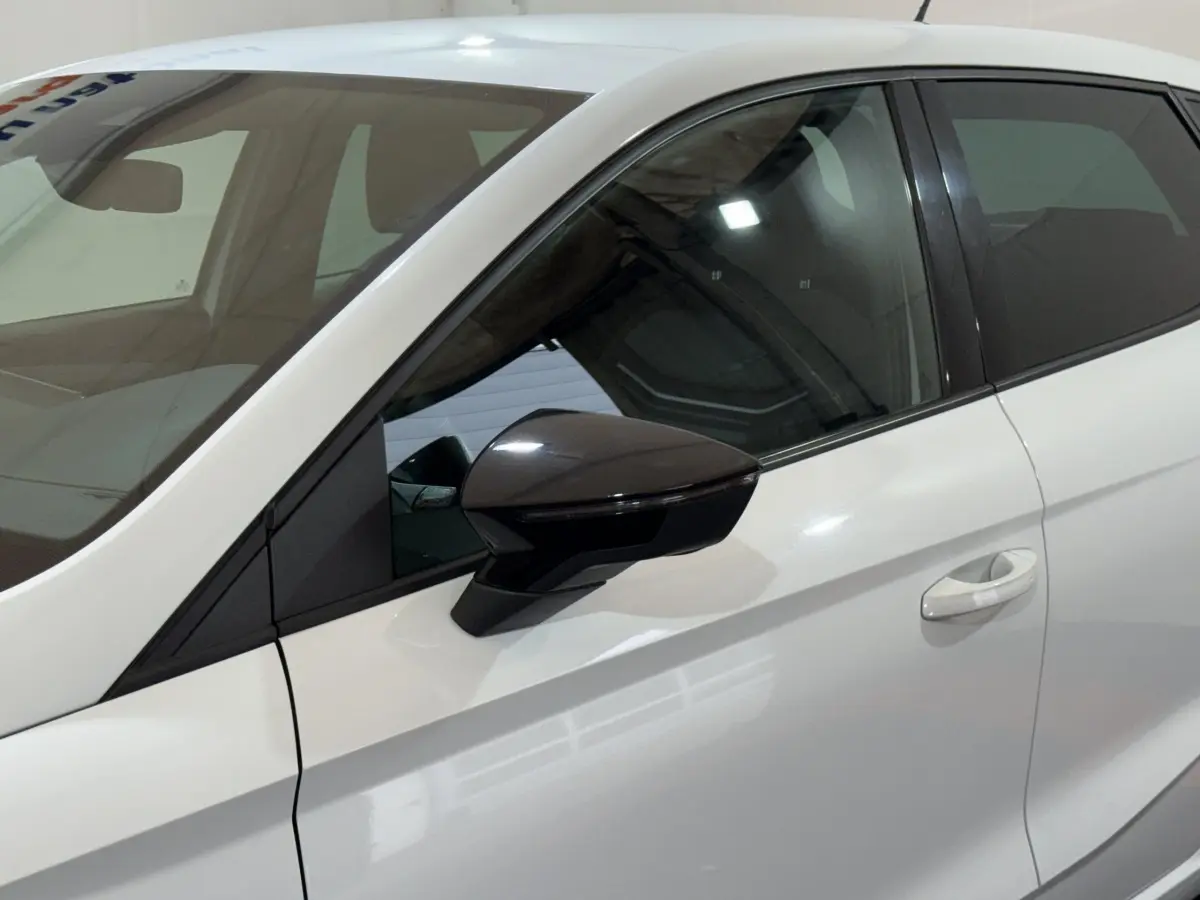 Vue côté gauche rapprochée d’une SEAT Ibiza blanche 2024, mettant en valeur la portière et le rétroviseur noir brillant.
