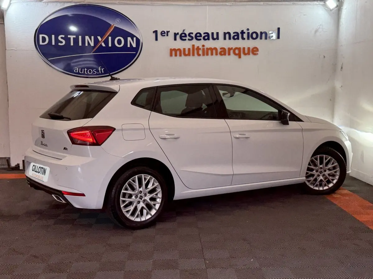 SEAT Ibiza 1.0 TSI 110 FR blanche vue de profil droit en intérieur, avec jantes alliage et feux arrière LED.
