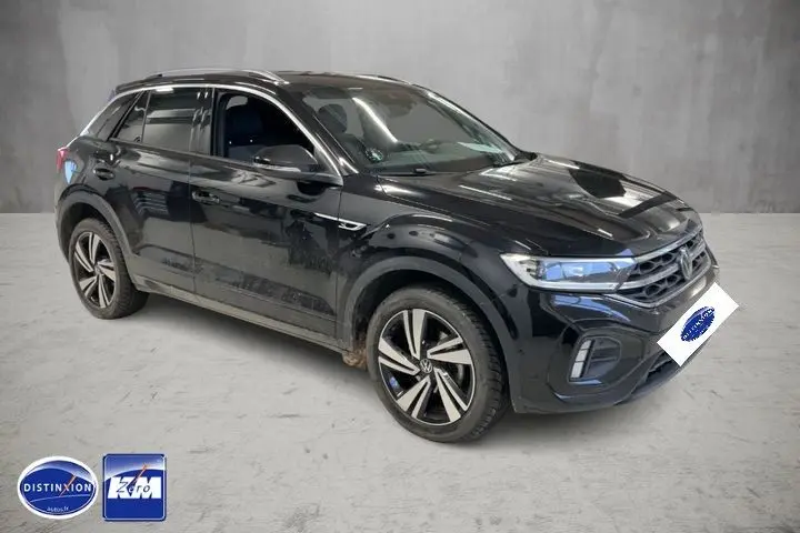 Volkswagen T-Roc noir intense en 3/4 avant droit, avec jantes bi-ton et finition R-Line visible.