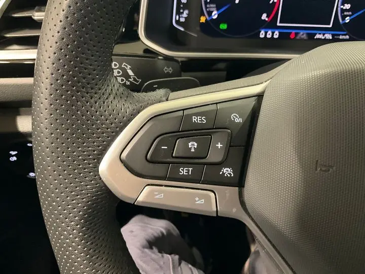 Gros plan sur le volant perforé du Volkswagen T-Roc 2025 noir intense, mettant en valeur les commandes de régulateur de vitesse.