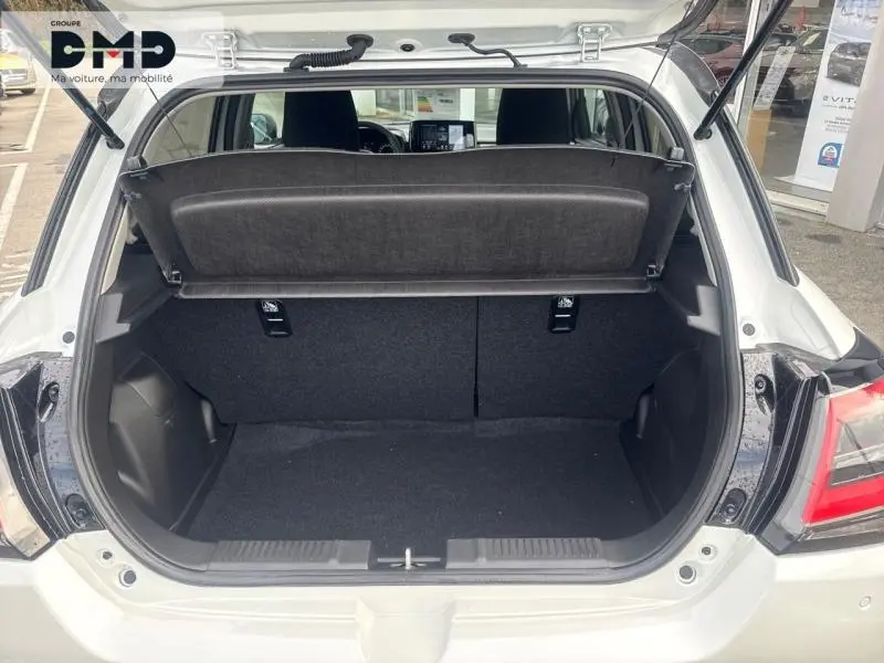 Coffre ouvert vu de l'arrière d'une Suzuki Swift 1.2 Hybrid blanche avec toit gris, intérieur noir et tablette cache-bagages.