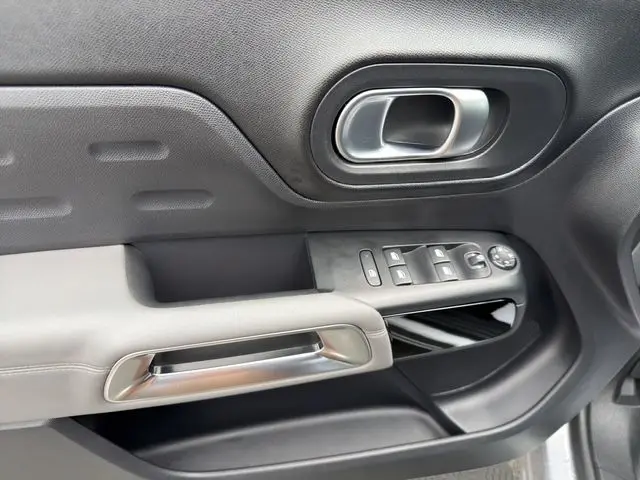 Vue rapprochée de la porte côté conducteur gris acier du Citroën C5 Aircross avec commandes des vitres et poignée argentée.