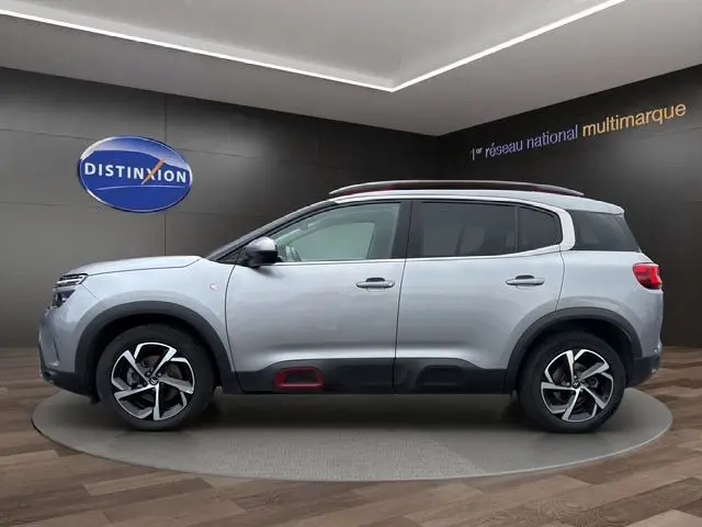 Vue latérale droite d'un Citroën C5 Aircross gris acier avec jantes alliage et inserts rouges sur les bas de caisse.