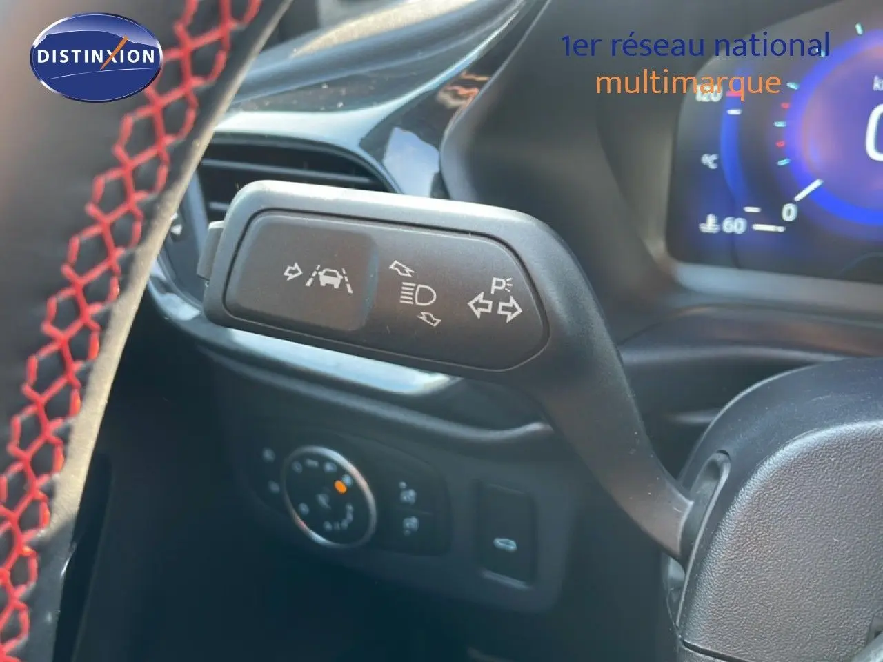 Gros plan sur la commande de clignotant et aides à la conduite du Ford Puma noir Agate Métal, intérieur avec volant cuir noir à surpiqûres rouges.