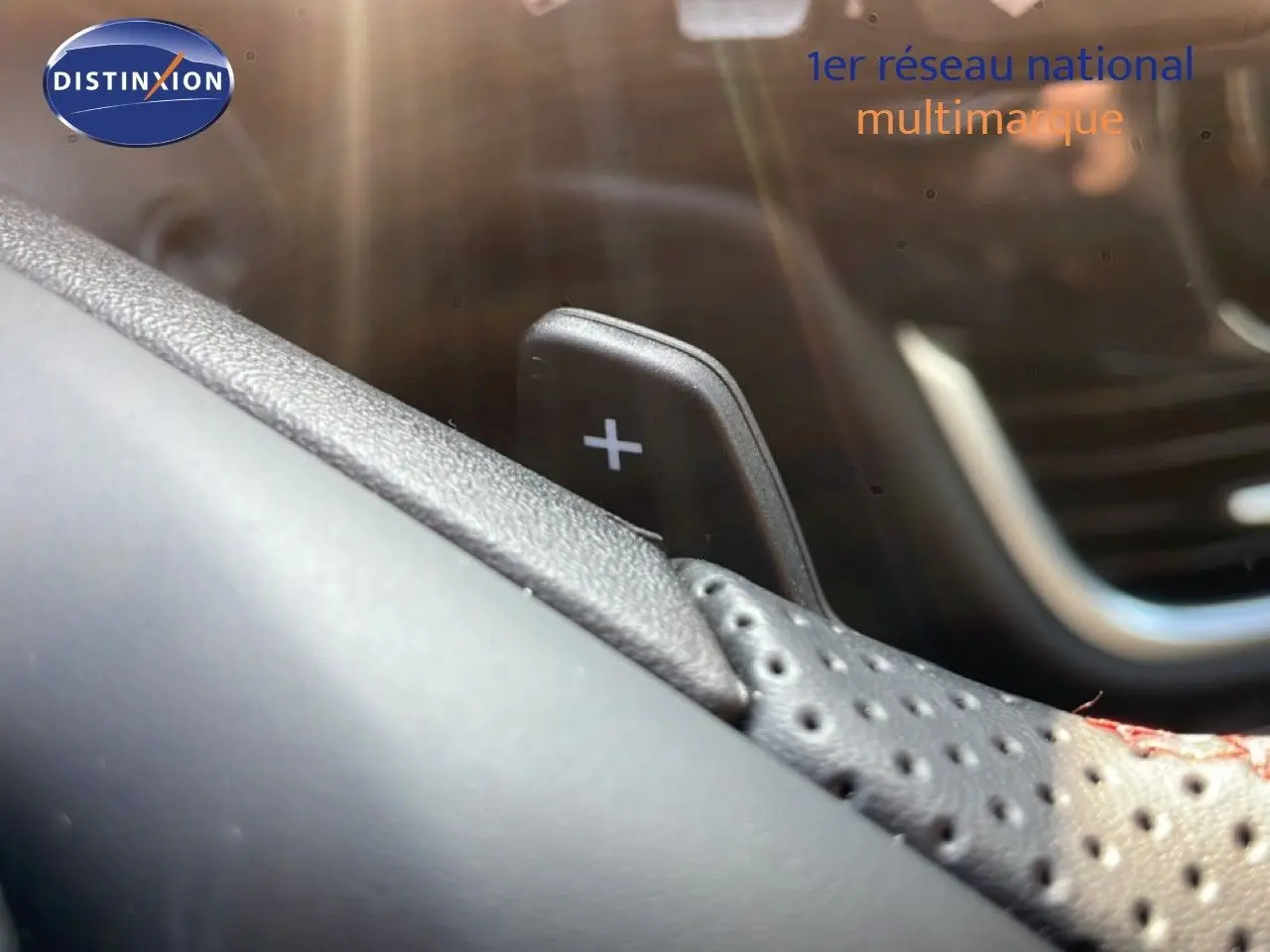 Gros plan sur la palette de changement de vitesse "+" en cuir perforé noir à surpiqûres rouges dans un Ford Puma 2023.