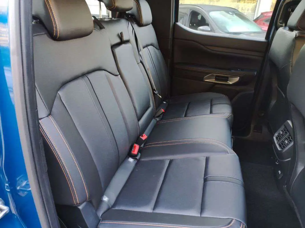 Vue intérieure côté droit des sièges arrière en cuir noir avec surpiqûres orange du Ford Ranger 2026 Bleu Lightning.