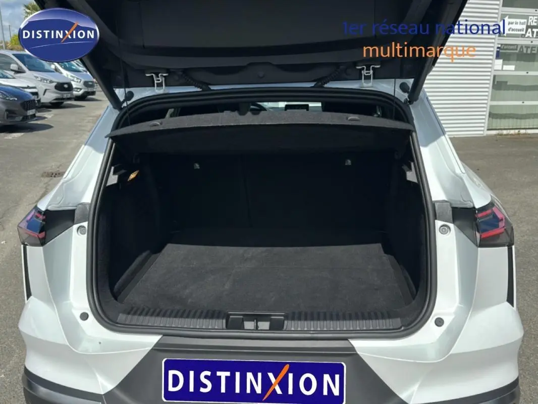 Vue arrière ouverte du coffre d'une Renault SYMBIOZ blanc, mettant en valeur l'espace de chargement vide et les feux arrière distinctifs.