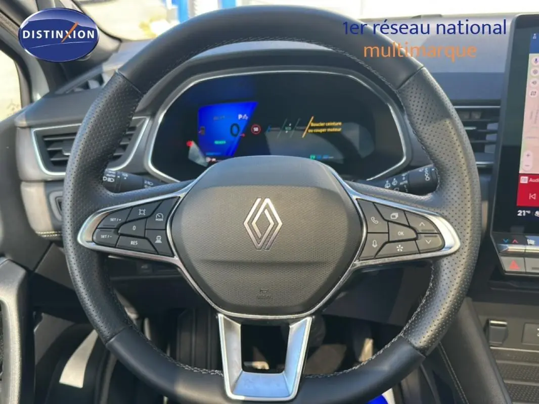 Vue intérieure centrée sur le volant noir perforé de la Renault Symbioz E-Tech 145 avec tableau de bord digital en arrière-plan.