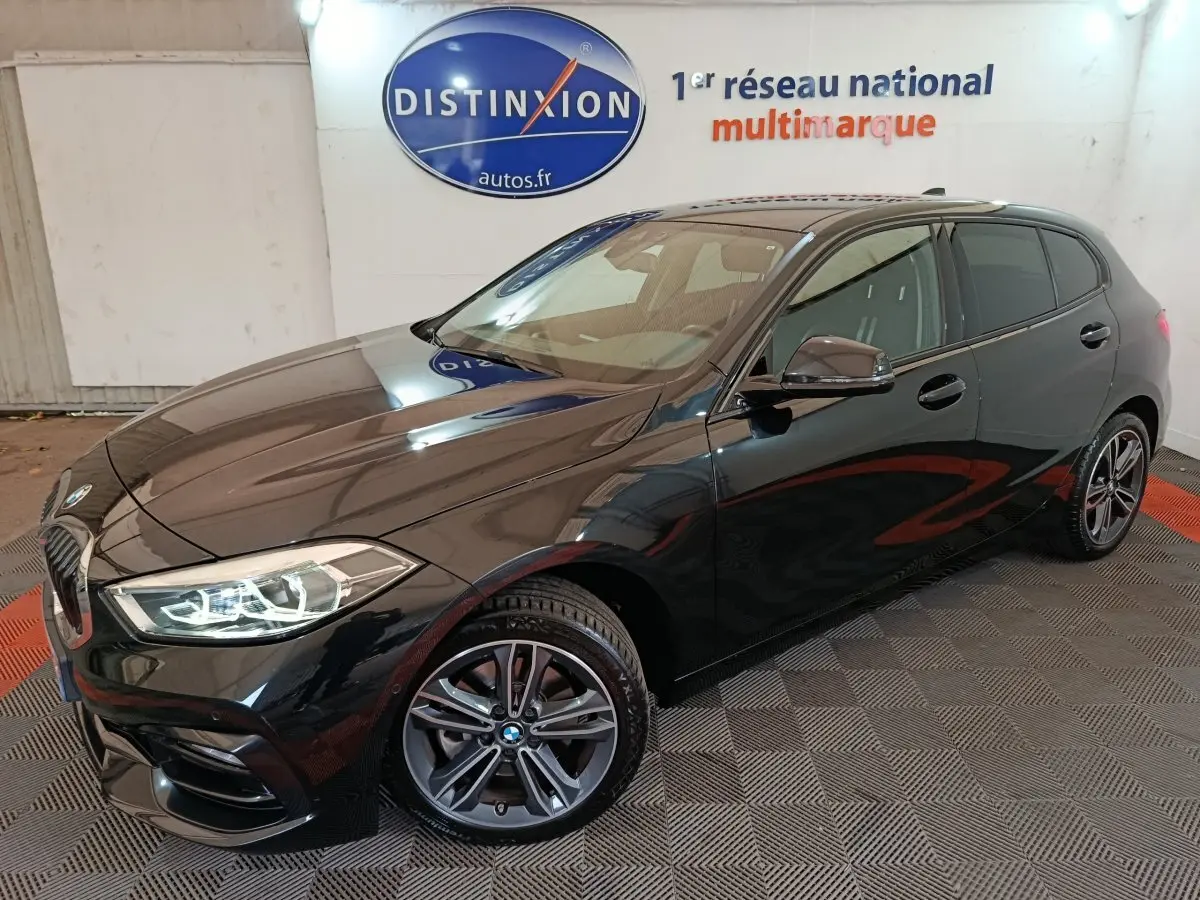 BMW Série 1 118i Edition Sport noire vue en 3/4 avant, phares LED allumés et jantes alliage distinctives.