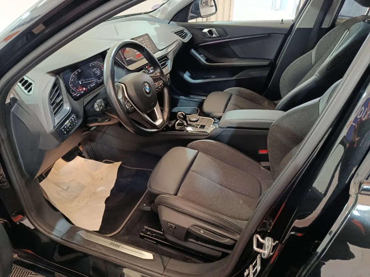 Intérieur noir de la BMW Série 1 118i Edition Sport 2023, vue côté conducteur avec tableau de bord et sièges avant.