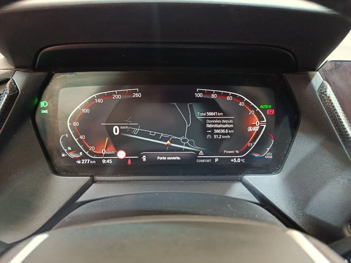 Vue rapprochée du tableau de bord numérique de la BMW Série 1 noire, affichant la vitesse et la navigation.