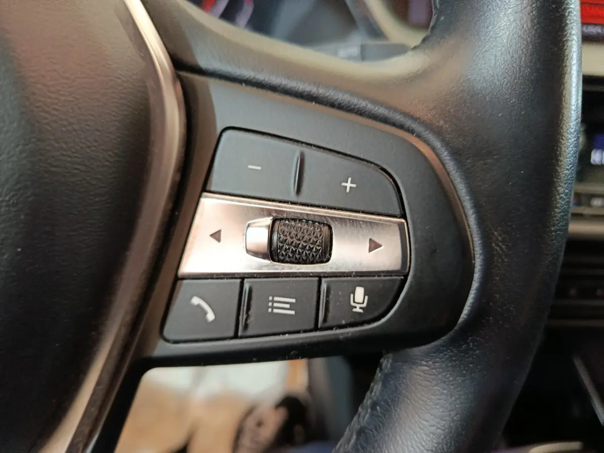Gros plan sur les commandes multifonctions du volant en cuir noir de la BMW Série 1 118i Edition Sport 2023.