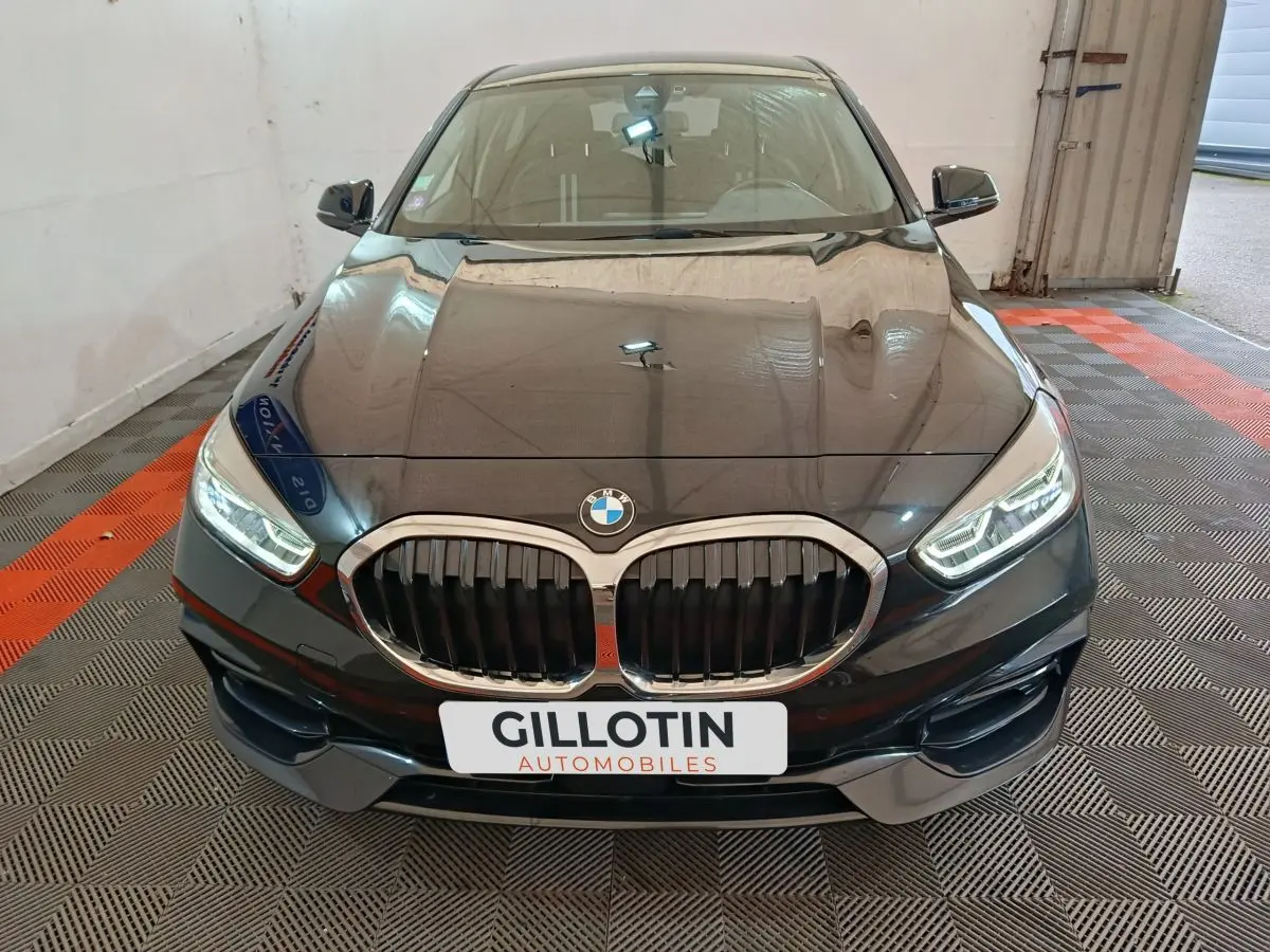 Vue avant rapprochée d’une BMW Série 1 118i Edition Sport noire avec calandre double haricot et phares LED allumés.
