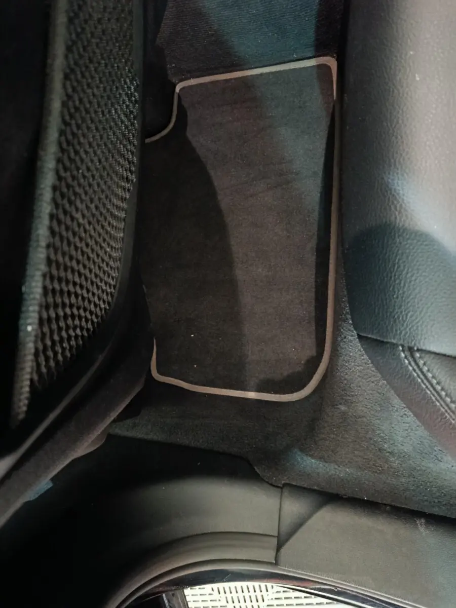 Vue rapprochée du tapis de sol noir avec surpiqûres claires côté passager arrière d'une BMW Série 1 118i Edition Sport 2023.