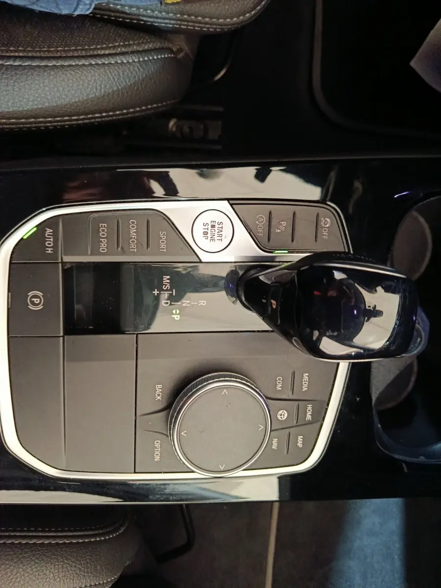 Vue rapprochée du sélecteur de vitesses et molette de contrôle central noir brillant dans une BMW Série 1 118i Edition Sport 2023.