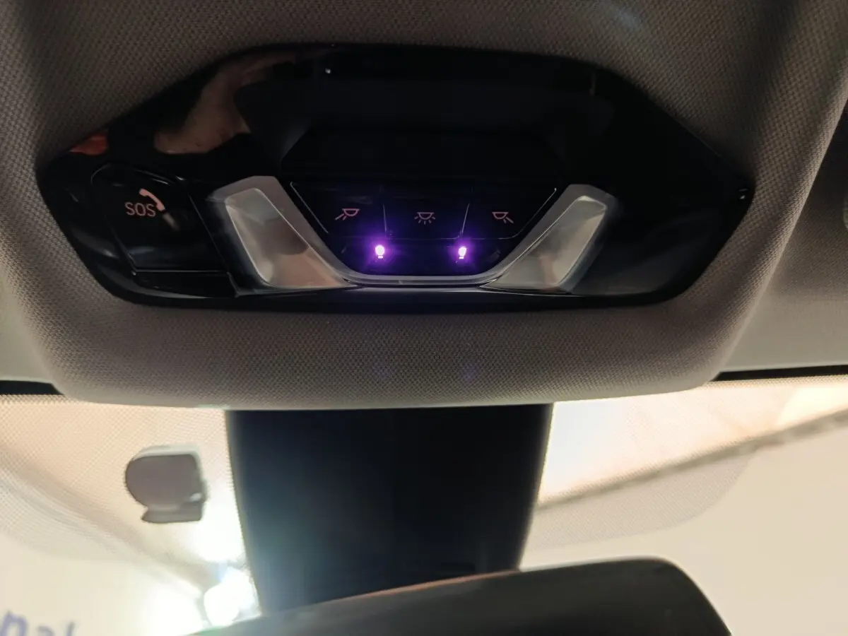 Vue intérieure du plafonnier avec boutons de commande et éclairage violet sur BMW Série 1 118i Edition Sport noire 2023.