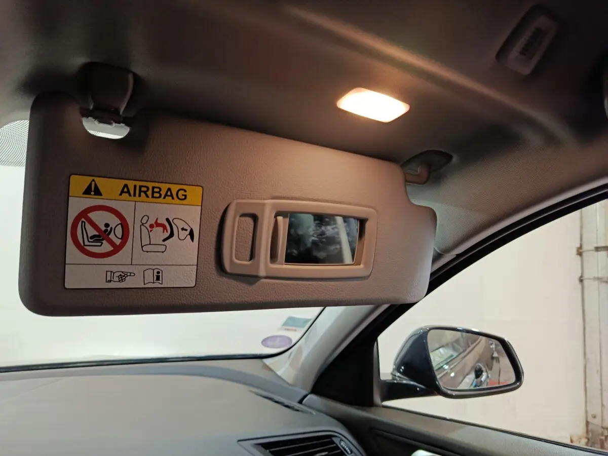 Détail intérieur côté conducteur de la BMW Série 1 noire 2023 montrant le pare-soleil avec miroir et éclairage.