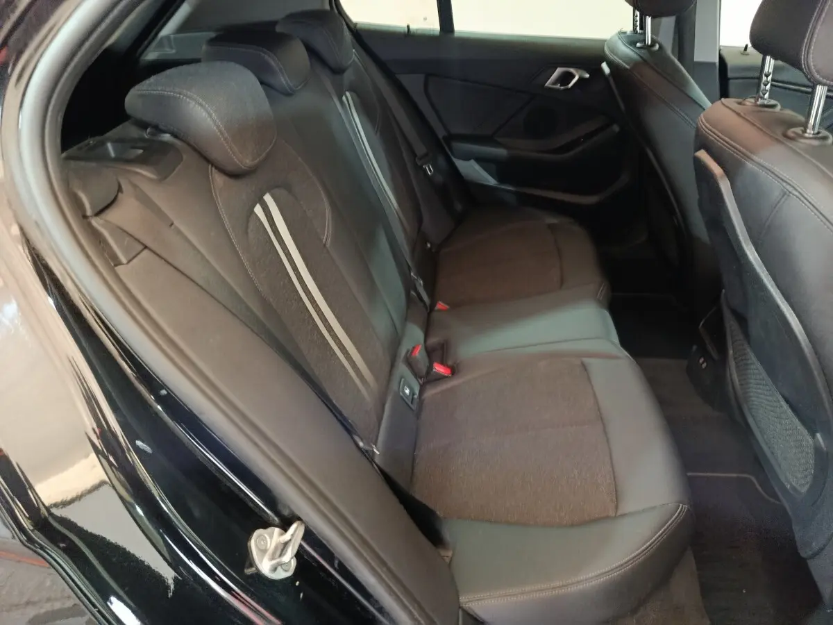 Vue intérieure côté gauche des sièges arrière noirs en tissu et cuir de la BMW Série 1 118i Edition Sport 2023.