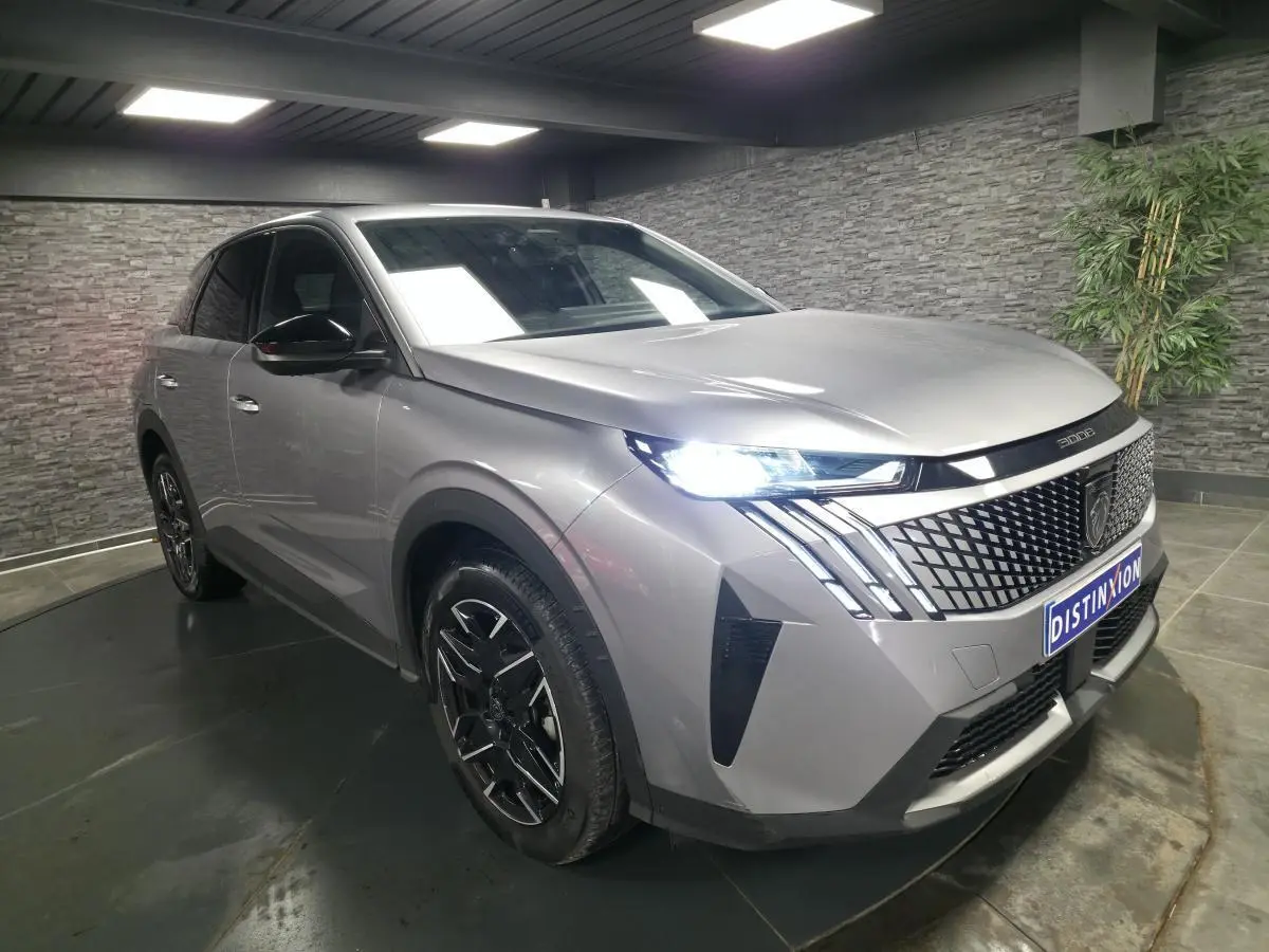 Peugeot 3008 gris métallisé en 3/4 avant droit, avec calandre noire laquée et feux LED allumés.