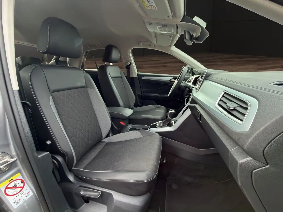 Vue intérieure côté conducteur du Volkswagen T-Roc 2.0 TDI gris clair, sièges tissu et cuir avec tableau de bord moderne.