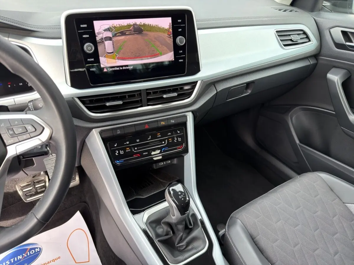 Vue intérieure côté conducteur du Volkswagen T-Roc 2025 avec écran tactile affichant la caméra de recul et levier de vitesse DSG.