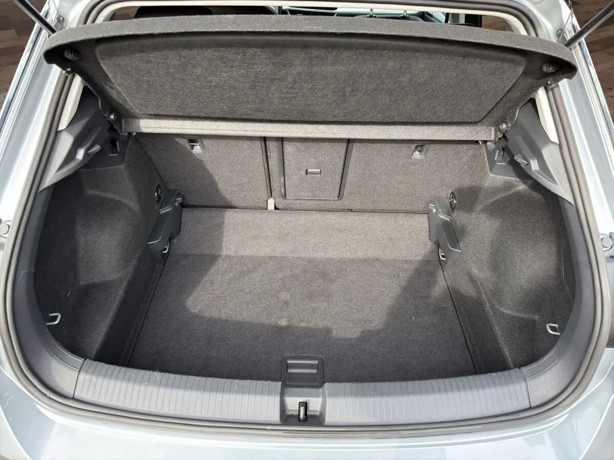 Coffre ouvert vu de l'arrière d'un Volkswagen T-Roc gris clair, espace de chargement propre et vide.