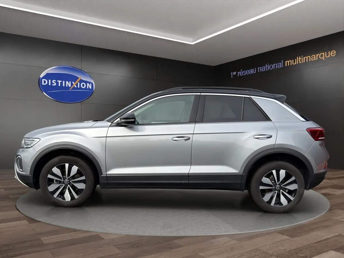Vue latérale droite d'un Volkswagen T-Roc gris clair 2025 avec jantes alliage et toit noir contrasté.
