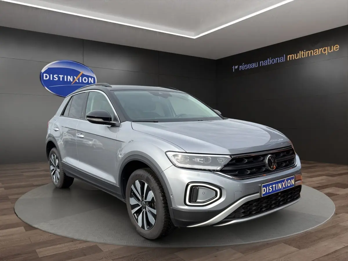 Volkswagen T-Roc gris clair en 3/4 avant droit, avec calandre noire et jantes alliage distinctives.