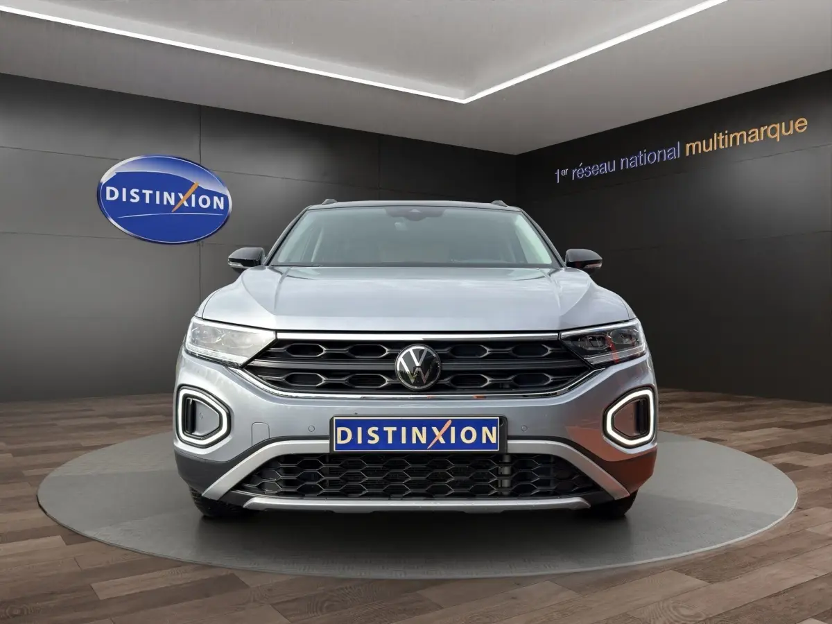Vue avant du Volkswagen T-Roc gris clair 2025 avec calandre noire et feux LED en forme de C.