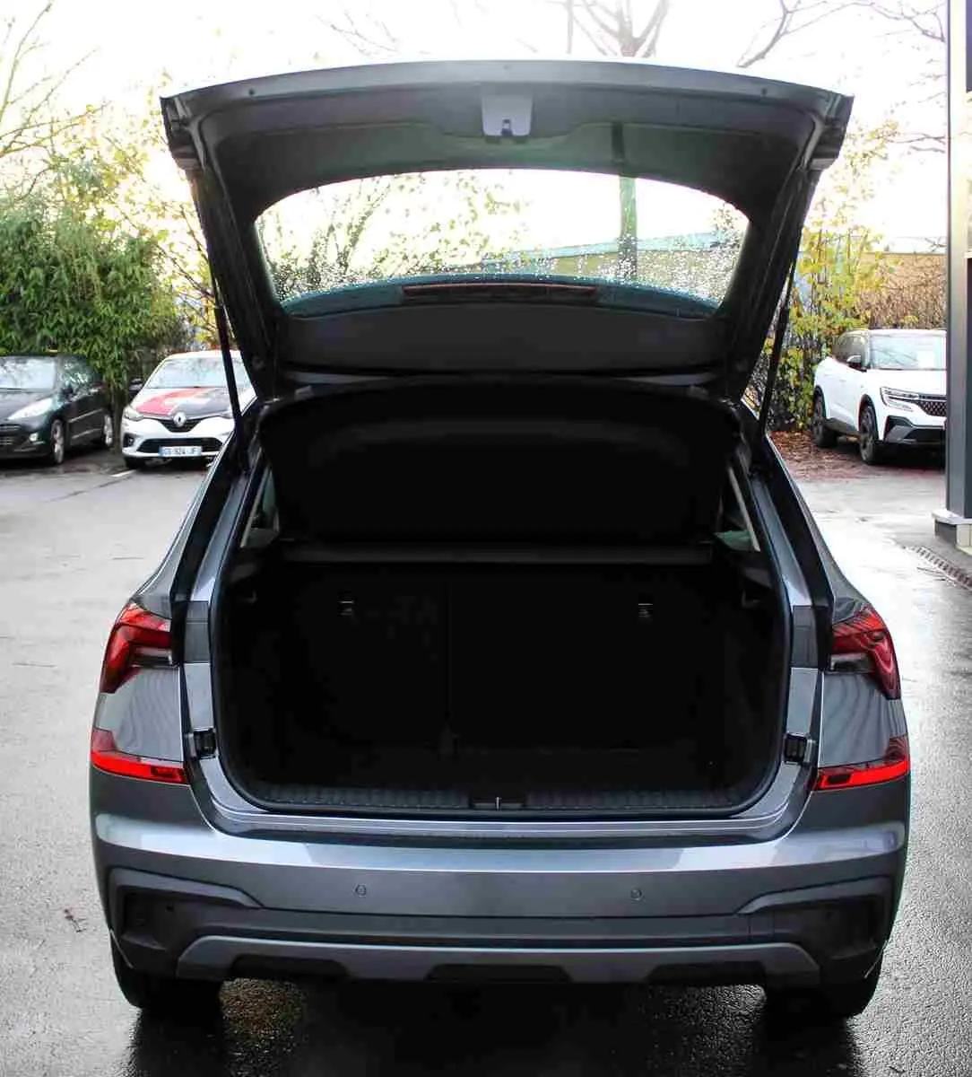 Vue arrière d'un Skoda Kamiq gris graphite 2025 avec coffre ouvert, mettant en valeur ses feux LED et son hayon spacieux.